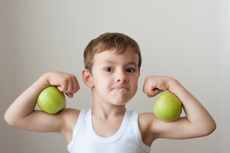 boy with green apples showing biceps